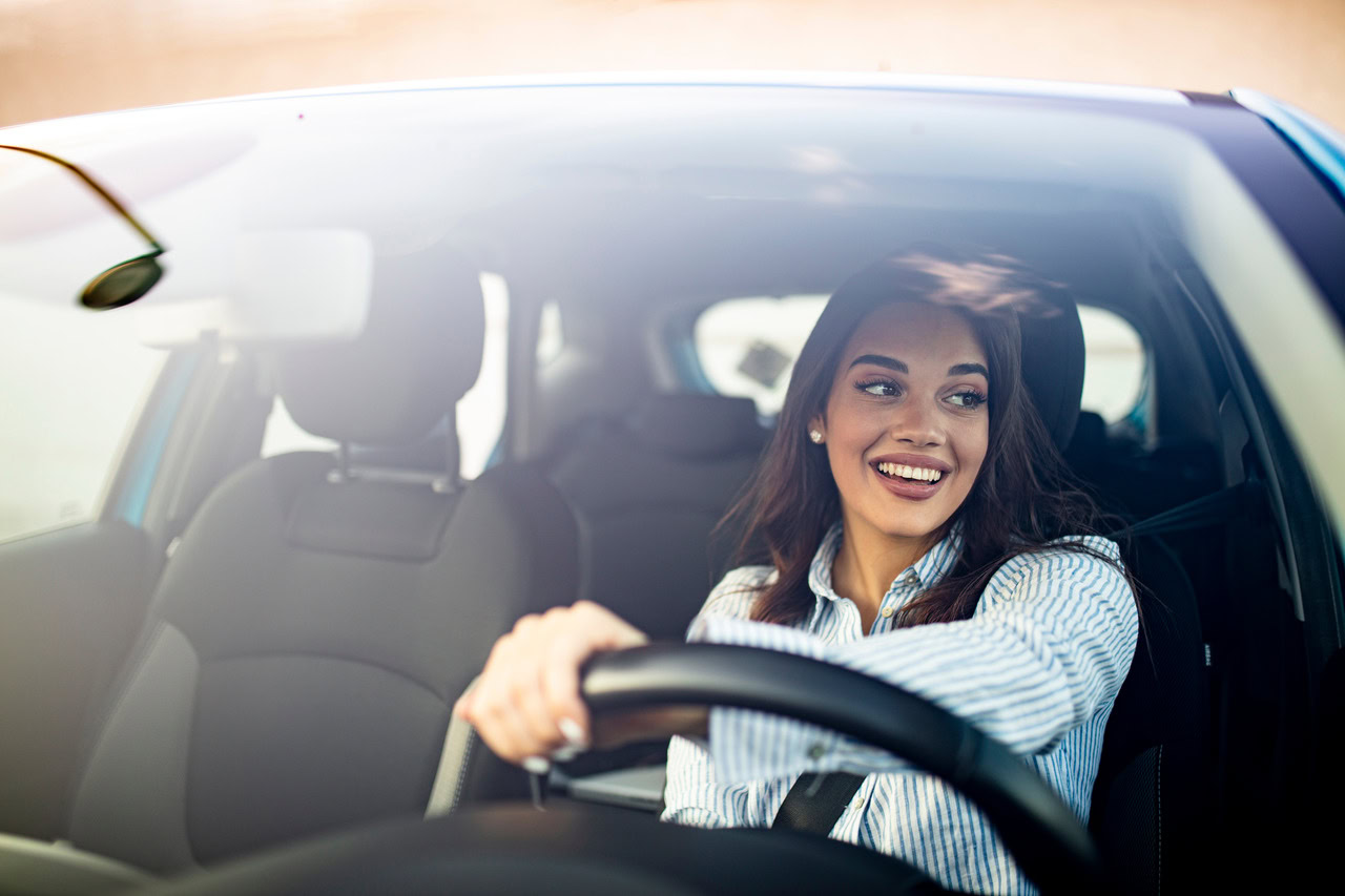 Colaboradora de uma empresa em uma viagem corporativa dirigindo um carro para falarmos sobre os acordos com locadoras de carros.