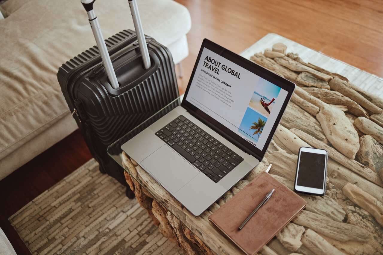 notebook ao lado de uma mala de viagem para se referir ao papel das OTAs em viagens.