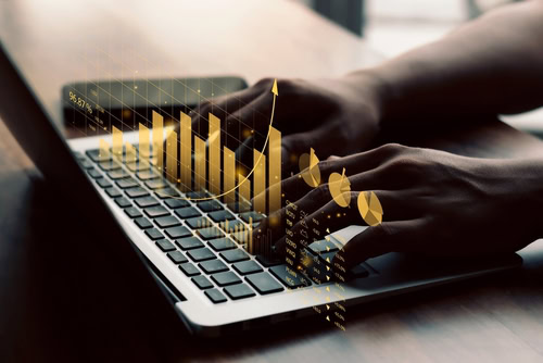 Mãos mexendo em um notebook com a tela das finanças corporativas da empresa.
