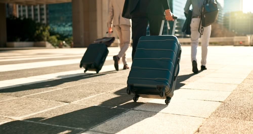 Imagem de viajantes corporativos andando com suas malas a fim de responder a seguinte questão: "posso me recusar a viajar pela empresa?".