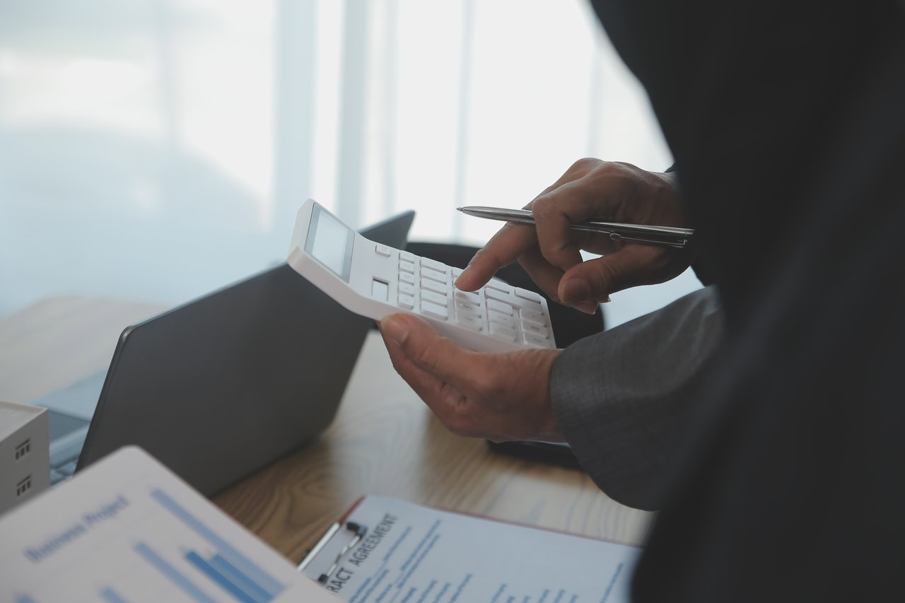 Colaborador com calculadora em mãos analisando uma ordem de compra.
