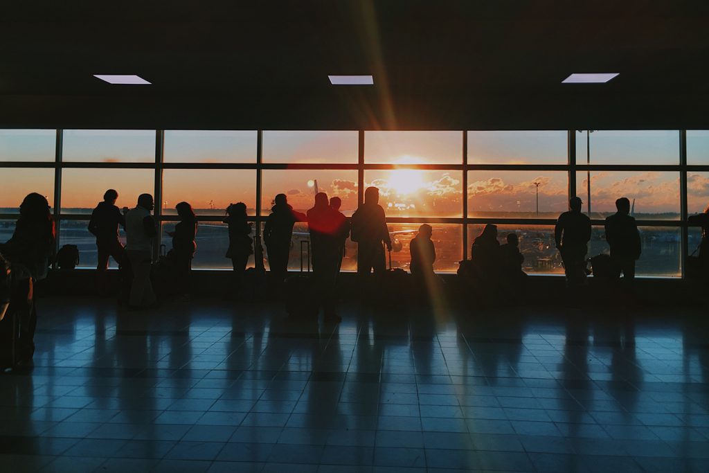 Diversas pessoas em um aeroporto fazendo alusão às viagens a trabalho, que envolve o processo de prestação de contas de viagens corporativas.