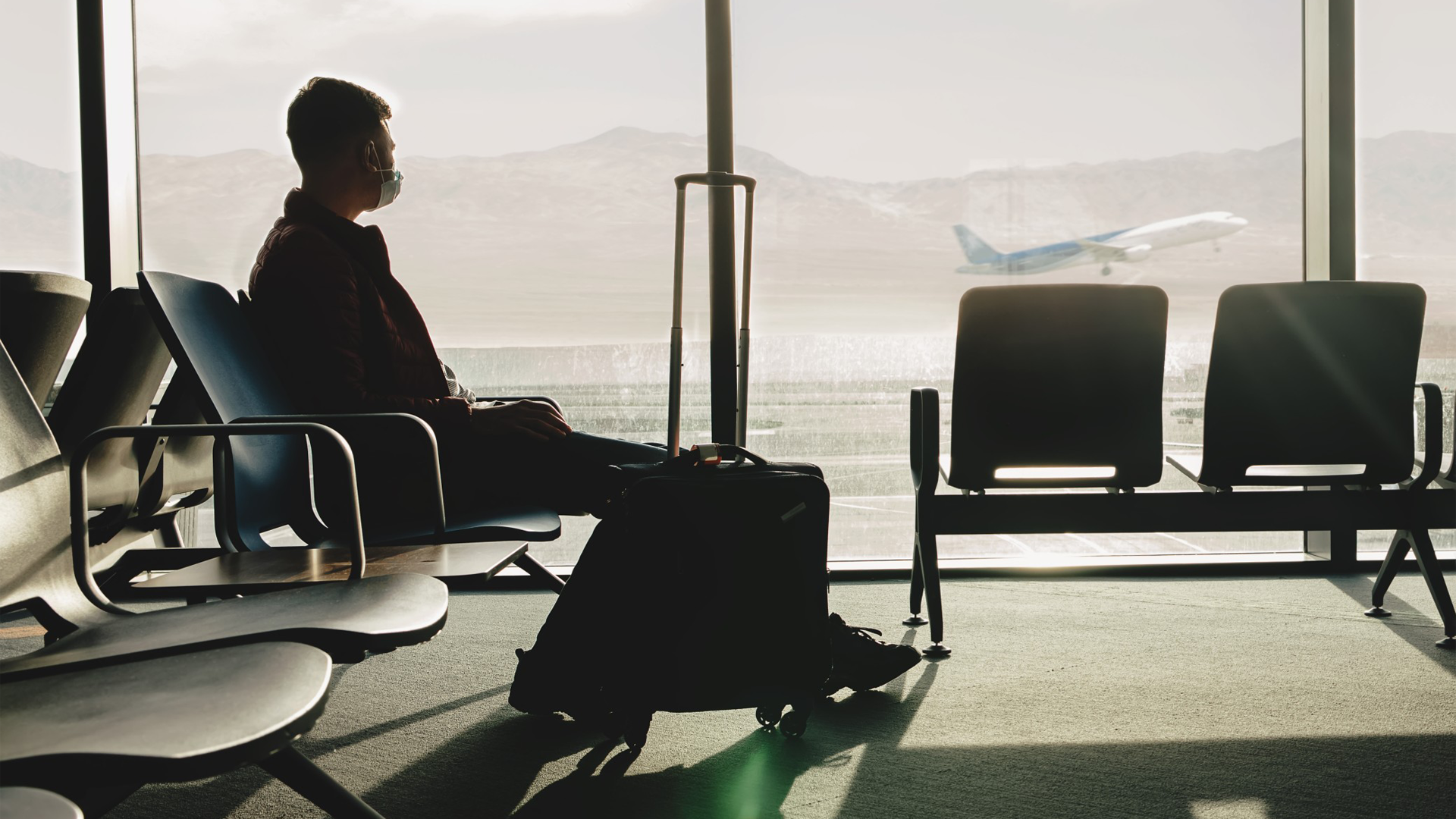 Profissional no terminal de embarque de um aeroporto à espera de um avião, dando a entender que a contratação de uma agência de viagens corporativas facilitaria a vida dele.