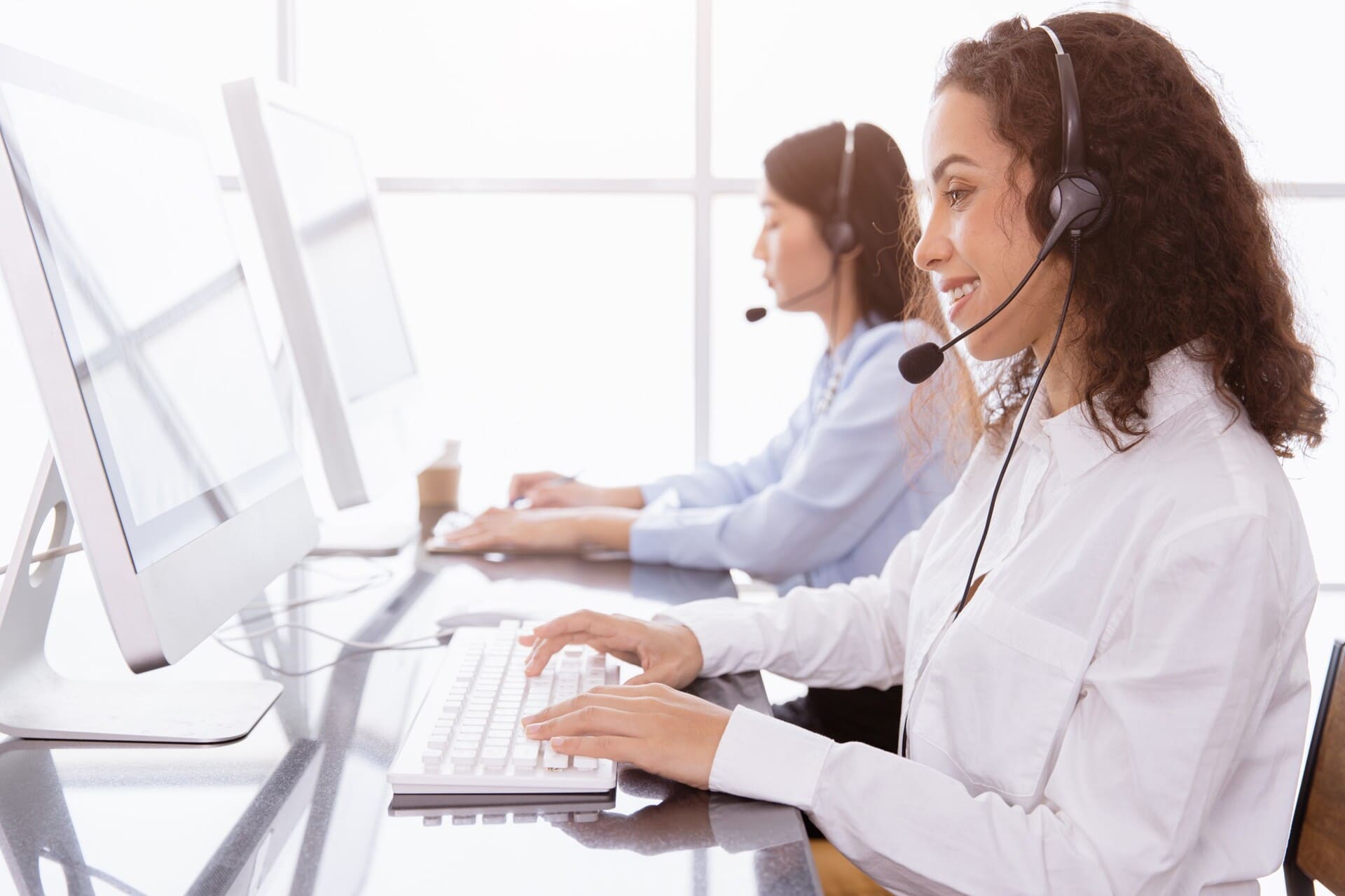 Duas profissionais à frente do computador realizando o atendimento 24/7 para empresas e colaboradores em viagens a trabalho.