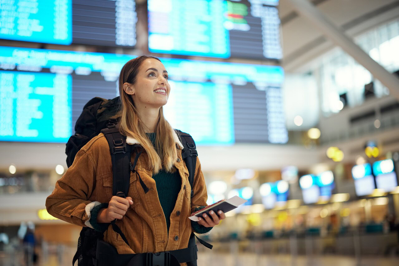 Mulher no aeroporto prestes a fazer uma viagem fazendo alusão a tecnologia NDC,