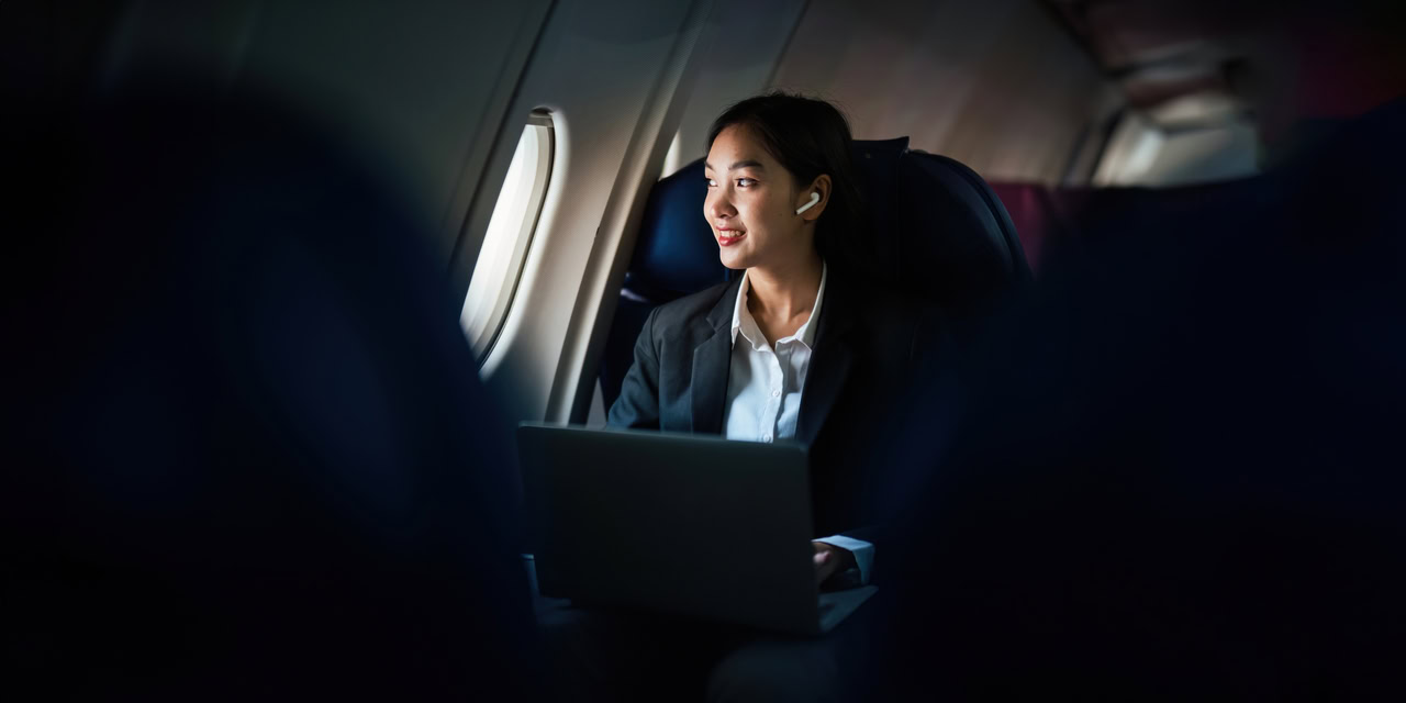 Mulher no avião olhando para janela a fim de trazer à luz quais são as melhores práticas para a gestão de viagens corporativas.