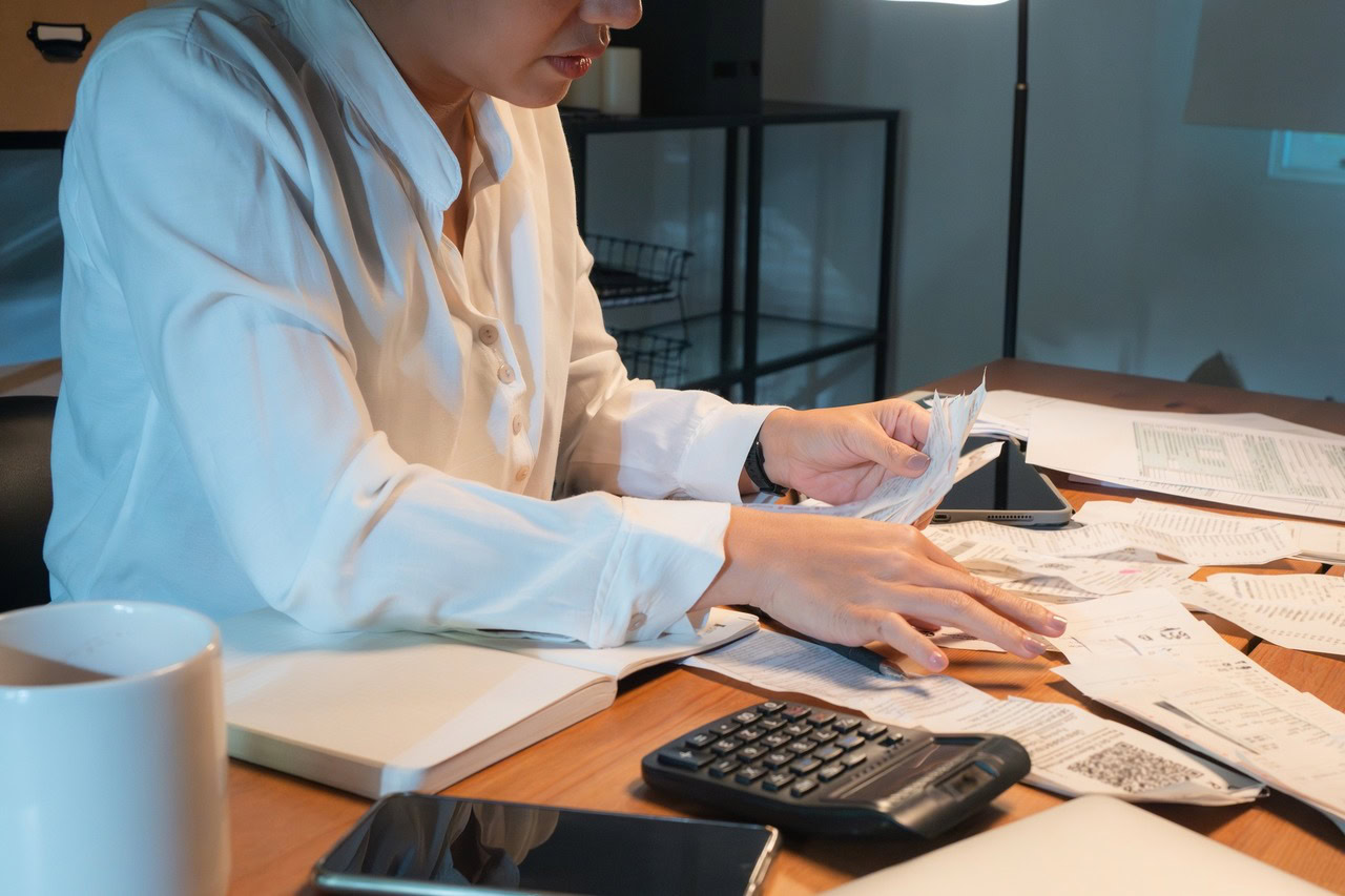Mulher trabalhando no escritório fazendo a classificação entre despesas fixas e variáveis da empresa.