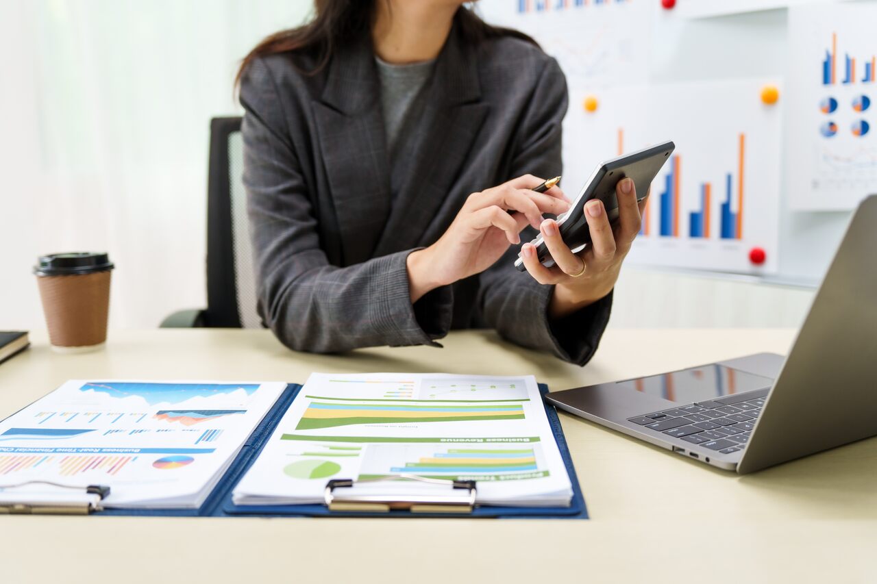 Mulher trabalhando com uma calculadora em mãos reforçando a importância do Expense Management.