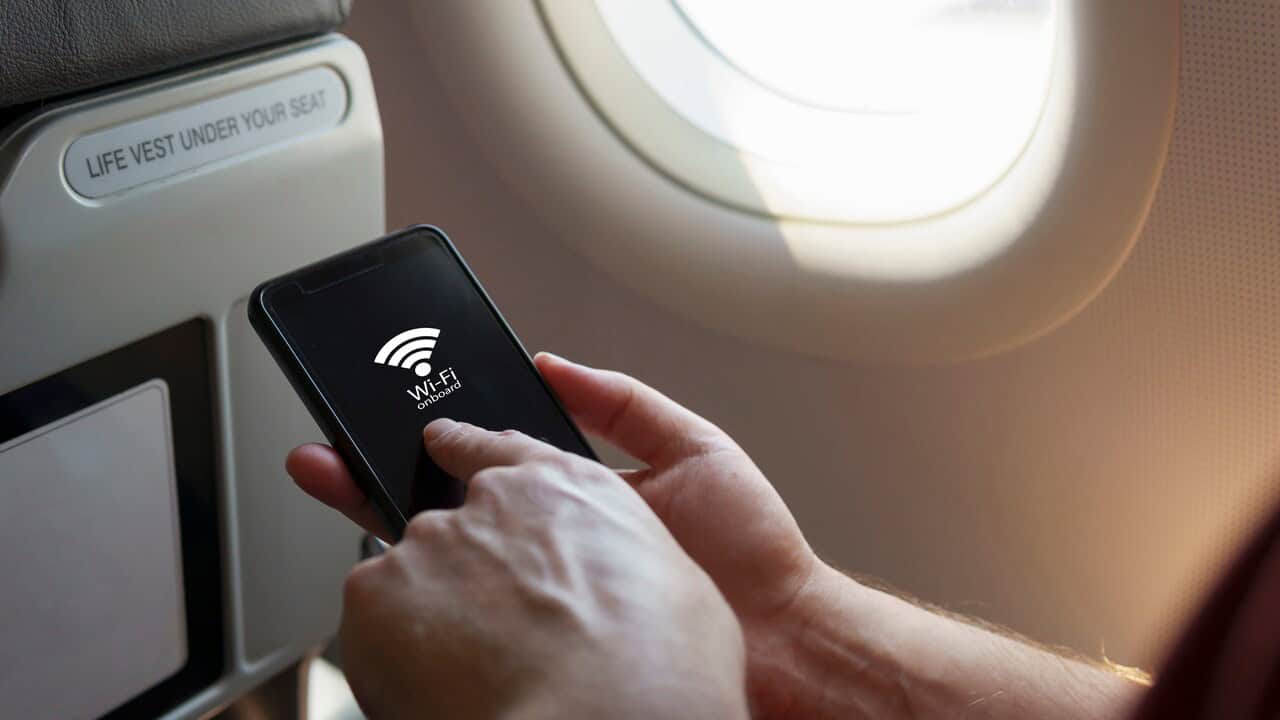 Pessoa no avião com o celular na mão tentando acessar o Wi-Fi.