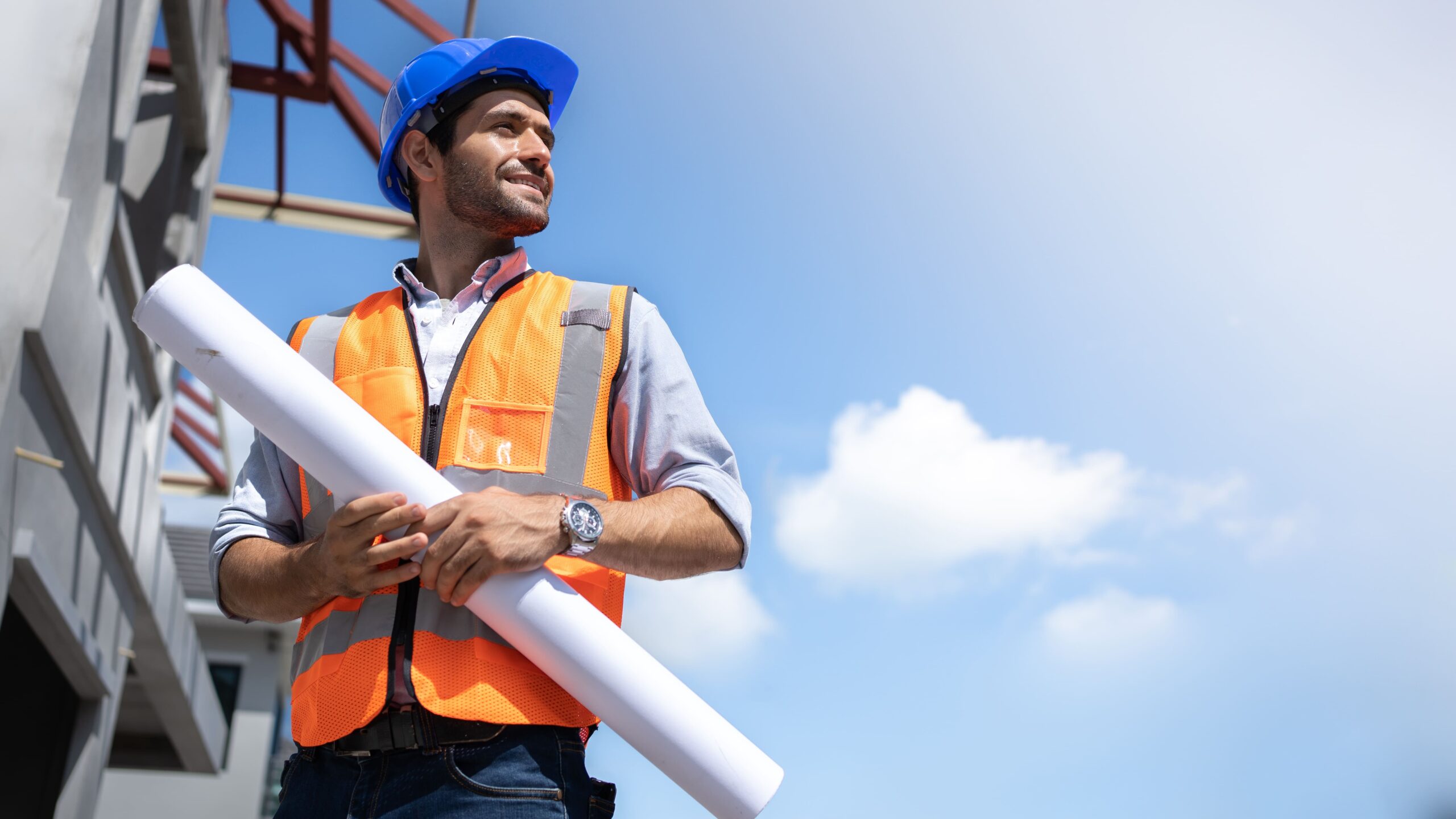 Engenheiro em um canteiro de obras vestido com EPI's e uma planta em mãos para abordar a importânjcia do BDI.