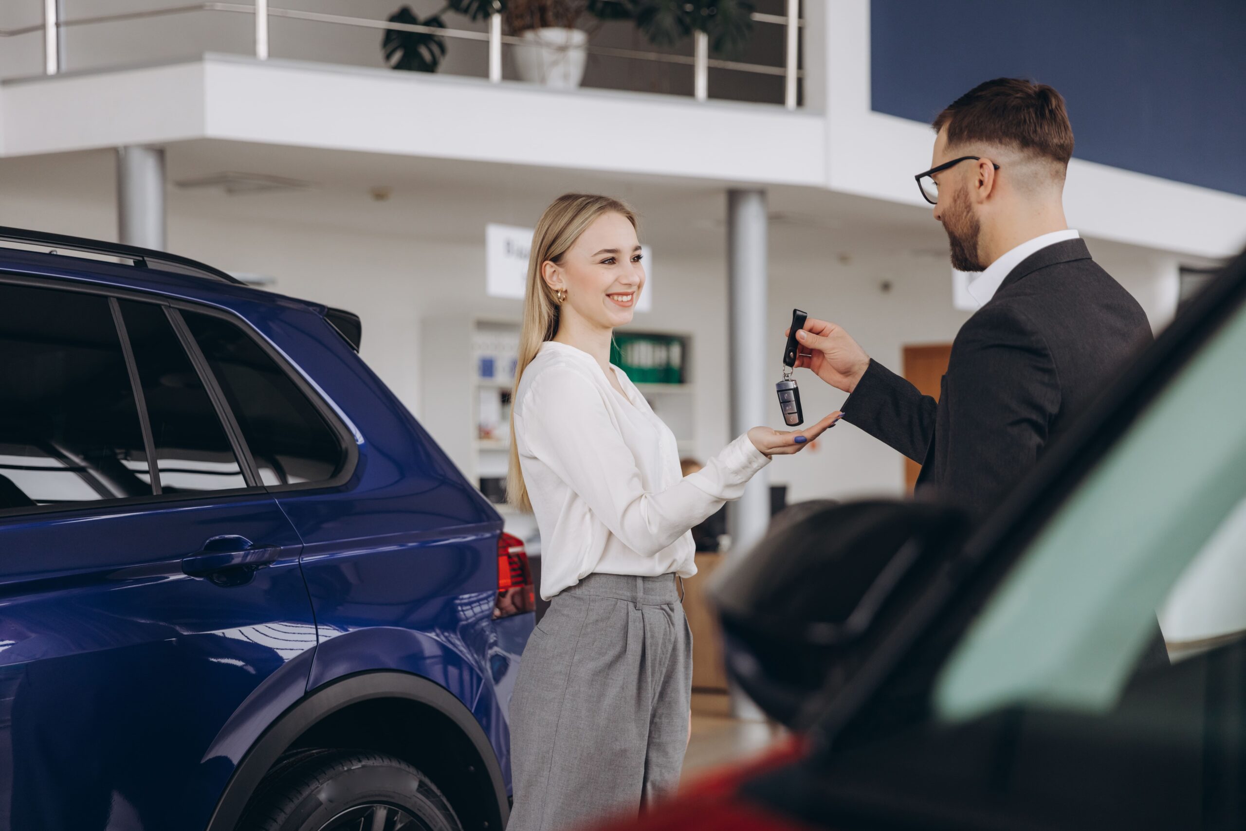 Mulher recebendo a chave de um veículo em uma locadora, após entender as categorias de carros para locação.