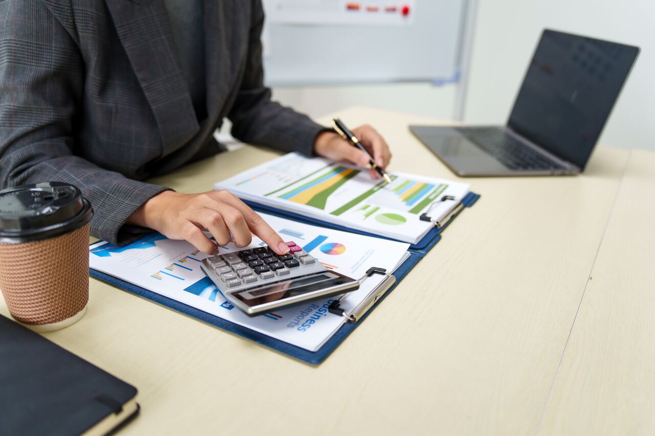 profissional trabalhando em sua mesa com uma calculacura analisando o índice de liquidez da sua empresa.
