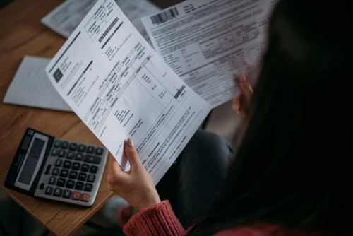 Mão segurando uma conta para realizar o pagamento de fornecedores.