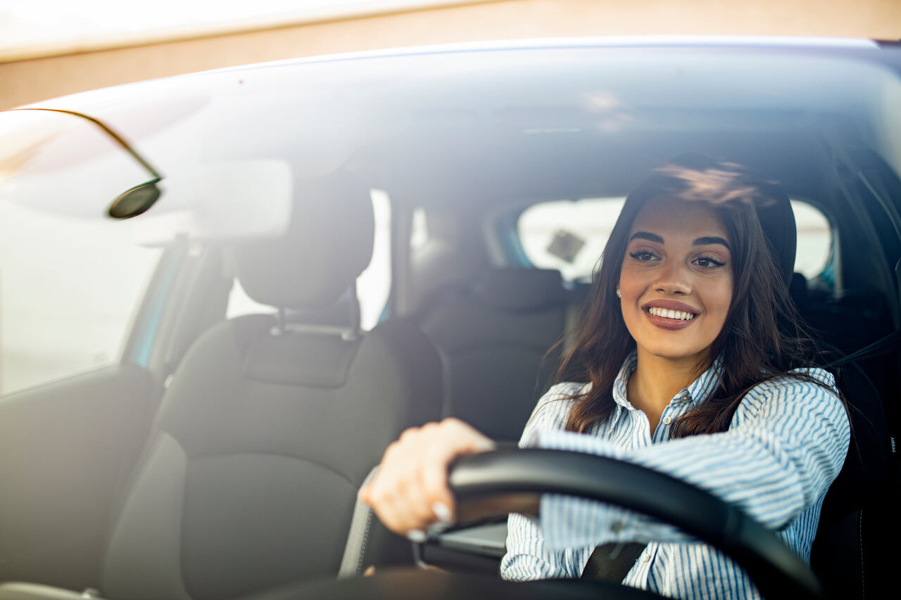 Mulher no seu carro em deslocamento para seu trabalho.